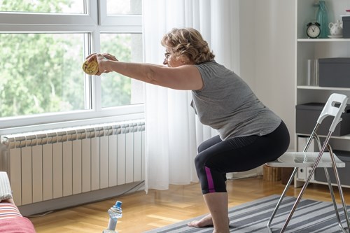 older woman doing squats on a chair