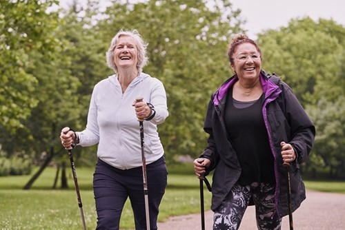 smiling women walking outdoors with walking poles