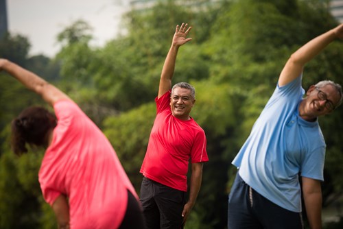 Group of three people doing stretches outdoors